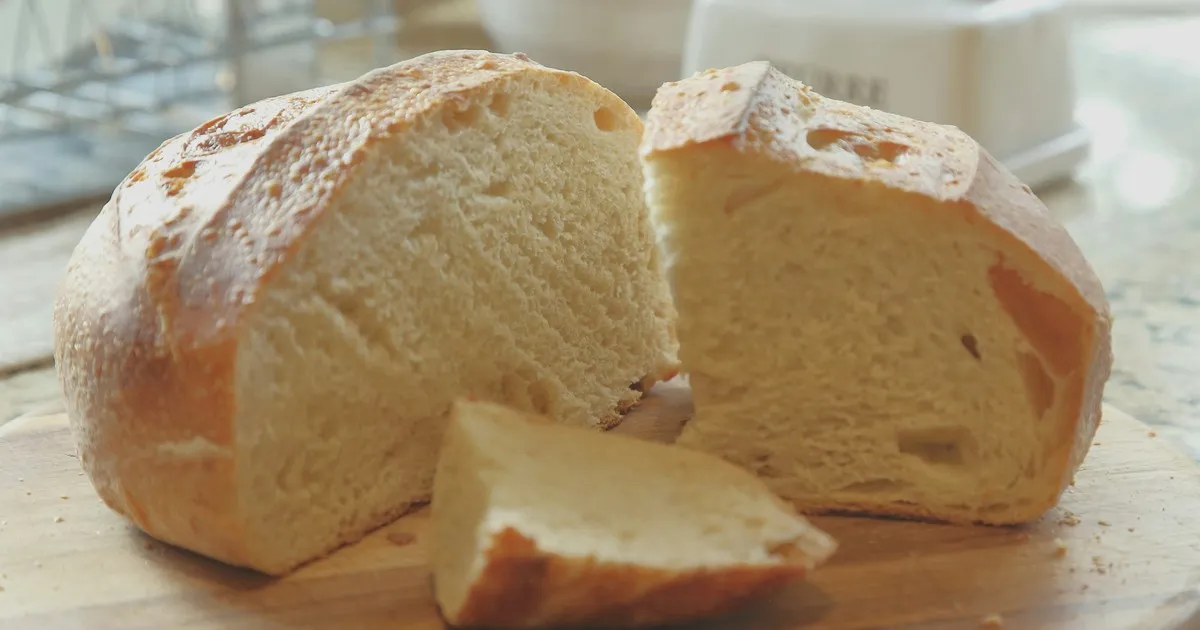 A sliced loaf of bread on a wooden board, one slice pulled to the side, untouched