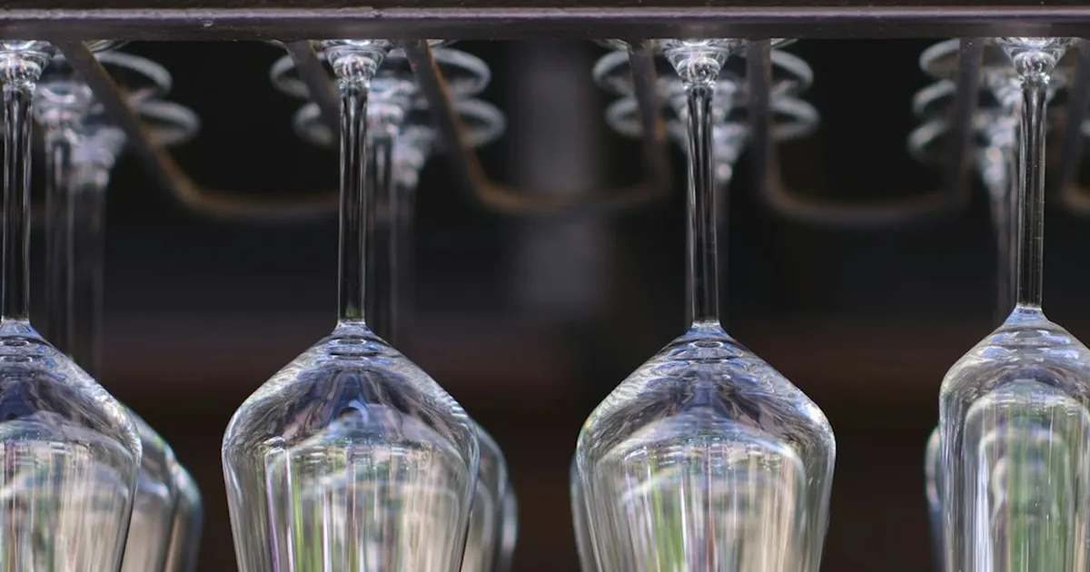 Empty wine glasses hanging upside down in a row from a rack